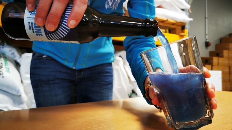 pouring blue beer into glass