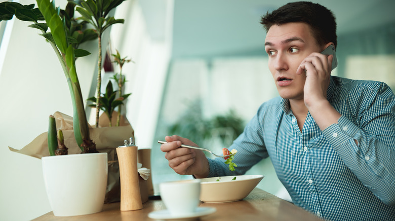 Man talking on phone while eating