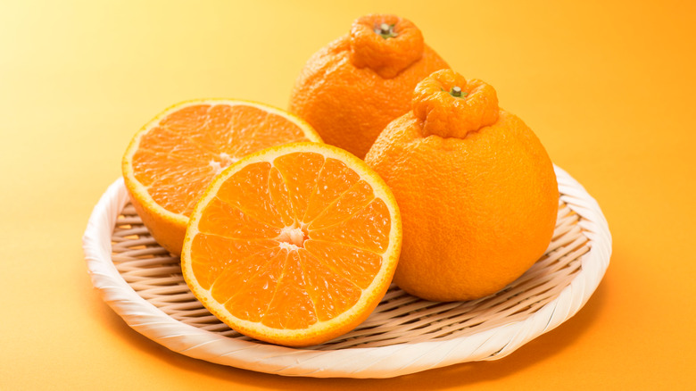 Whole and halved sumo oranges