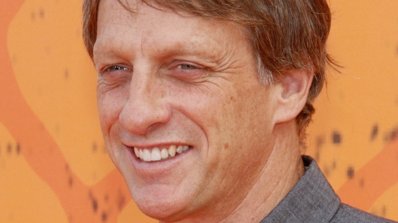 Tony Hawk with wide smile on orange background