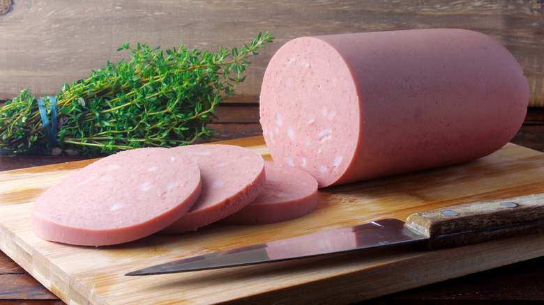 Large roll of bologna on cutting board