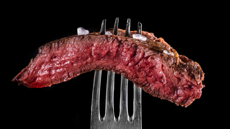 Slice of steak on fork with sea salt flakes