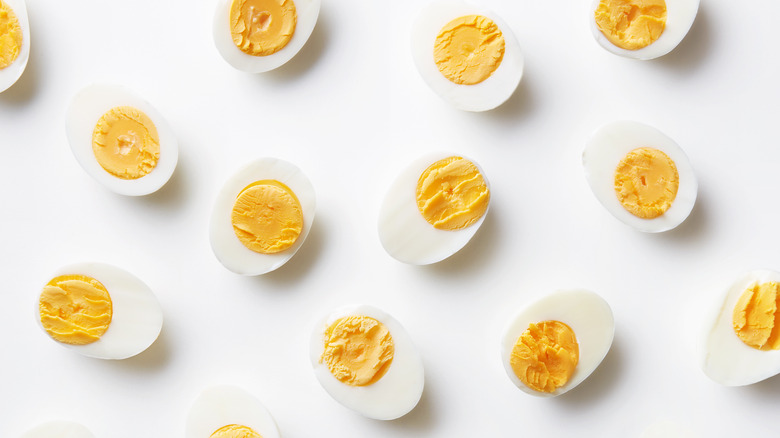 many halved boiled eggs on white background