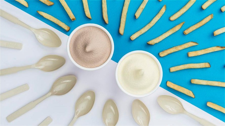 Wendy's chocolate and vanilla Frosty cups surrounded by spoons and fries