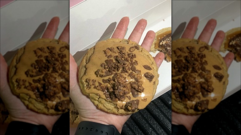 Person holding enormous peanut butter cookie