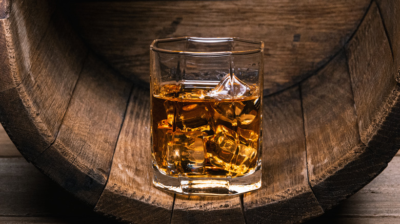 Glass of whiskey resting on a barrel