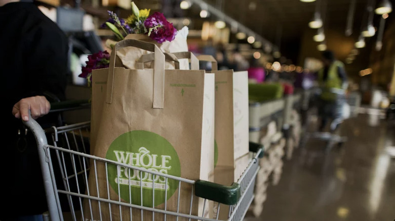 Shopping cart with Whole Foods paper bags and flowers