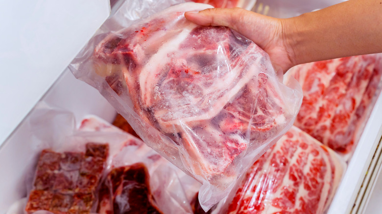 Person choosing raw beef ribs from freezer