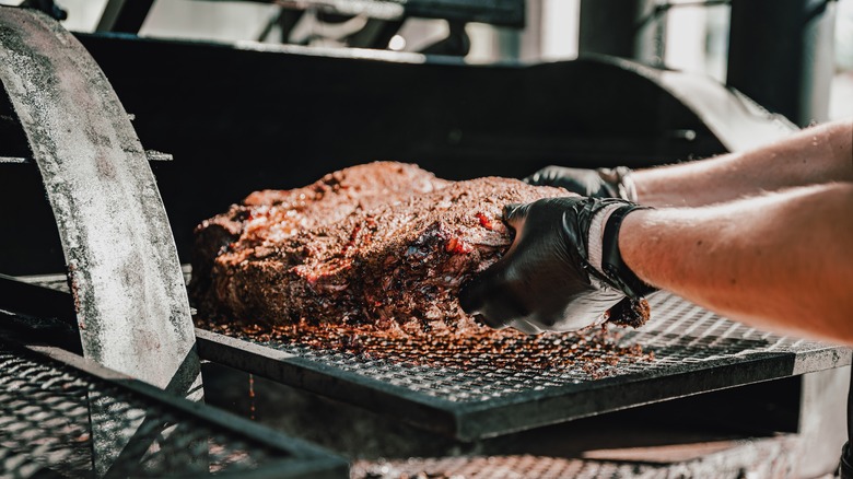 Brisket being handled in a smoker