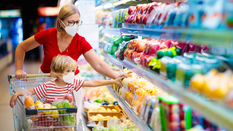 Woman and child in masks shopping at the grocery store