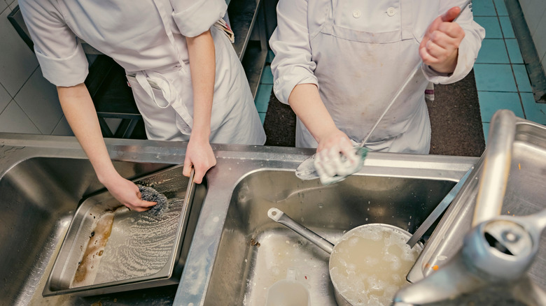 Restaurant employees washing dishes in sink