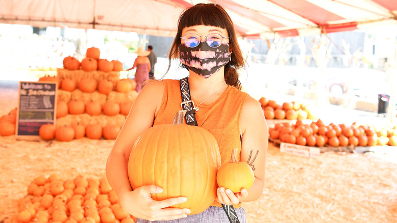 Person holding pumpkins at pumpkin patch