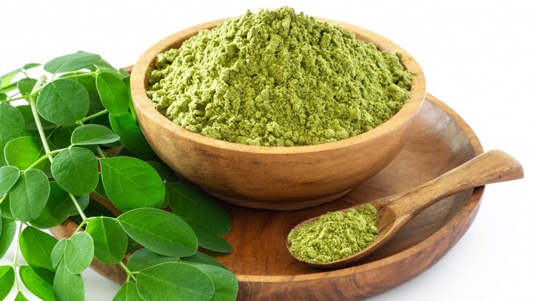 Green moringa powder in wooden bowl
