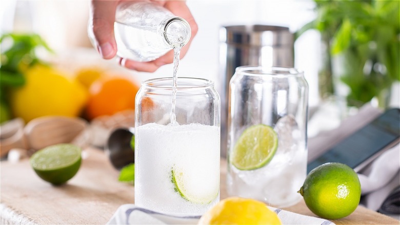 Hand pouring seltzer into glass 