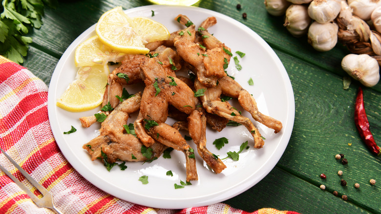 Frog legs on plate with parsley and lemon slices