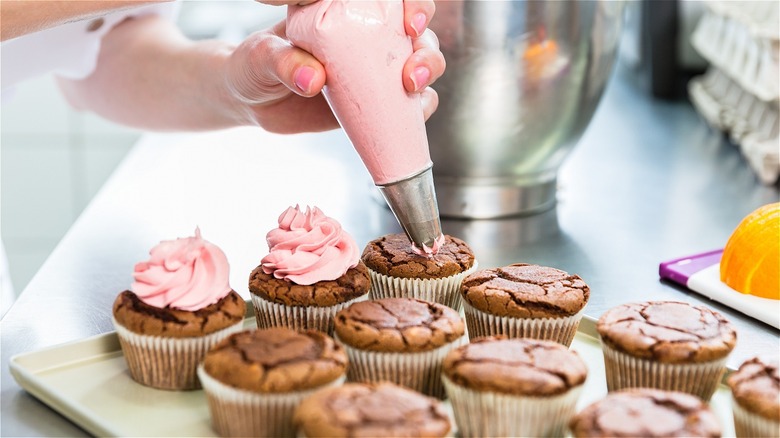 Piping frosting on cupcakes