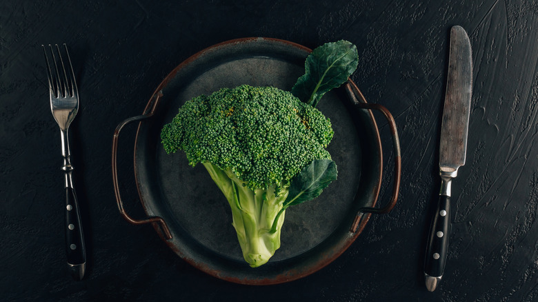 A head of broccoli on a black plate