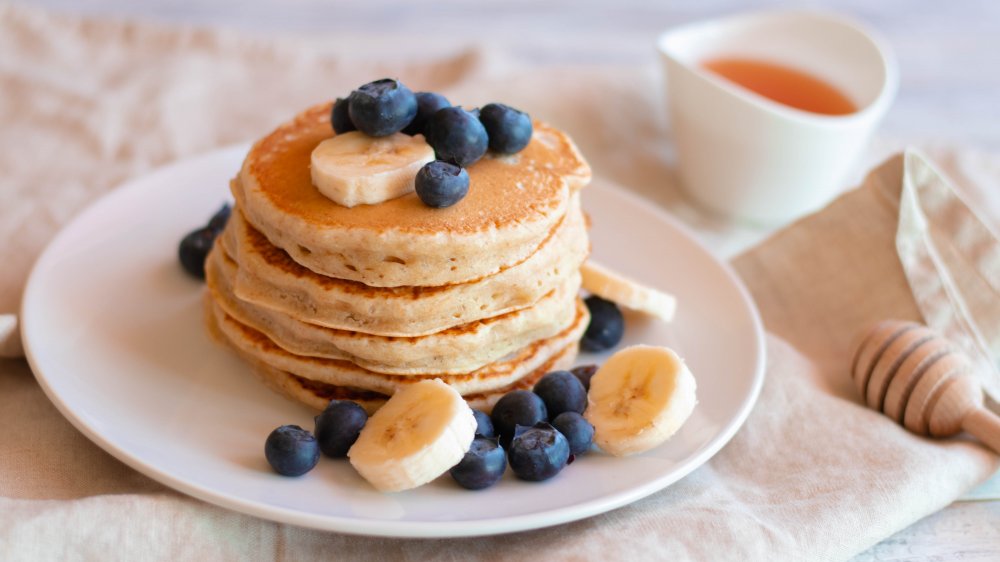 stack of pancakes topped with blueberries and banana slices