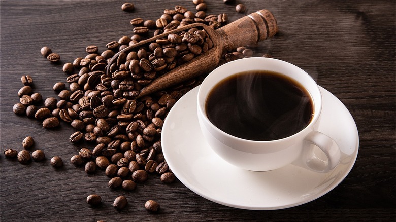 Coffee beans next to cup of coffee