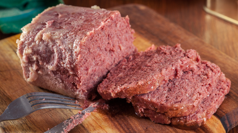 canned corned beef on cutting board with knife and fork