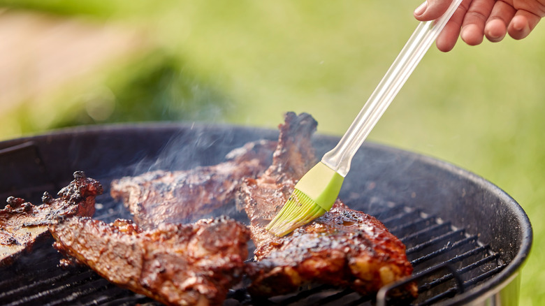 Brushing grilled meat with marinade