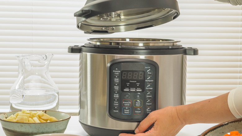 Person lifting lid off slow cooker
