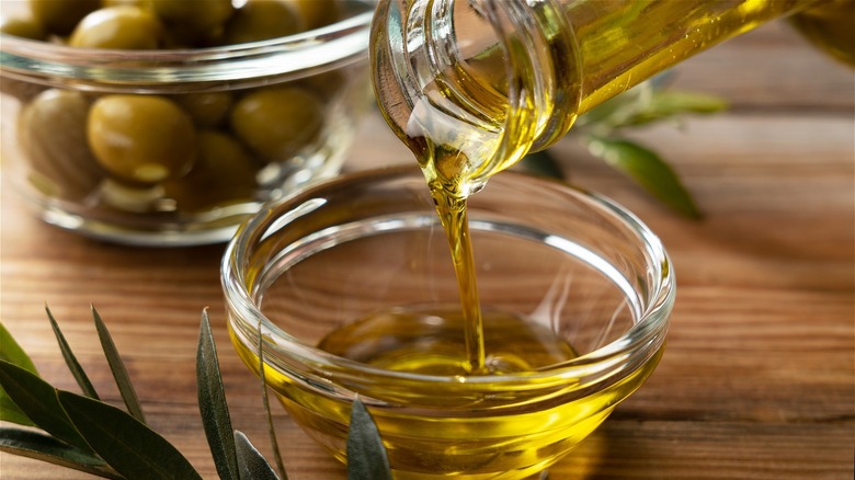 Olive oil pouring into glass bowl