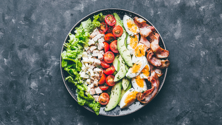 Bowl of salad with bacon on gray tabletop