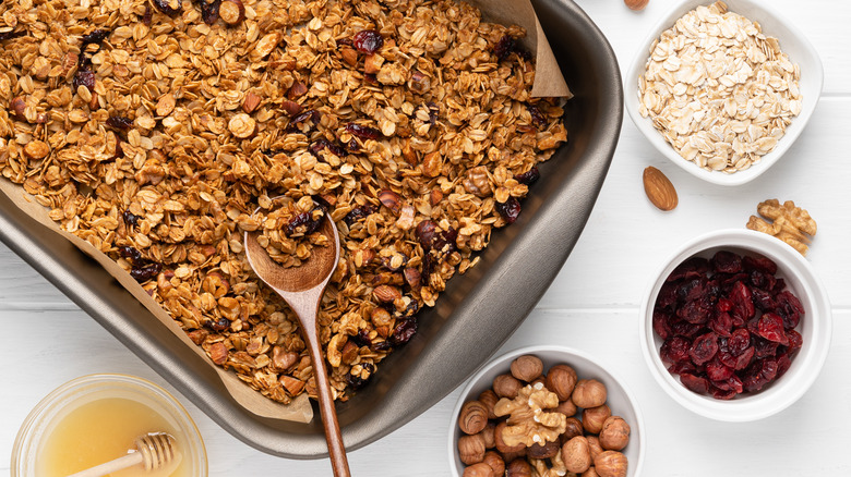 homemade granola in a baking tray with honey, dried fruit, oats, and nuts