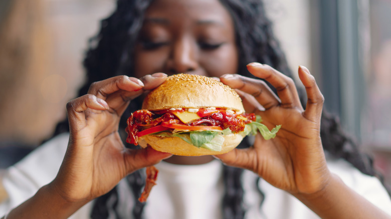 woman holding up bacon burger