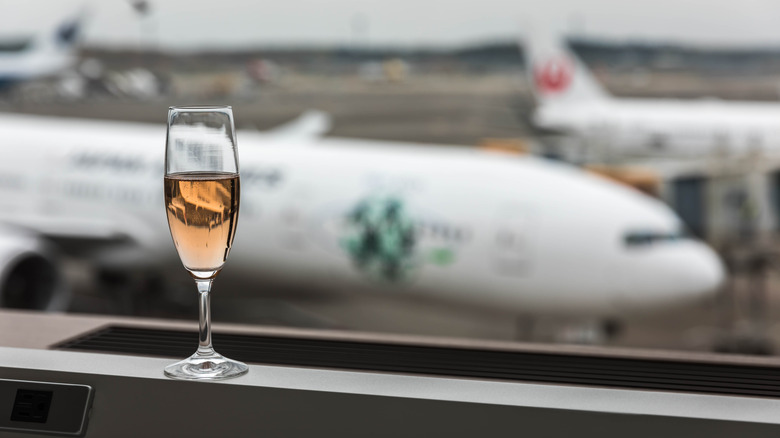 glass of champagne in front of airplanes in distance