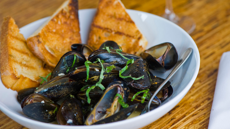 Cooked mussels in a white bowl 