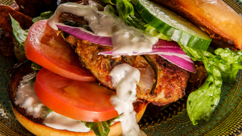 Burger loaded with meat, vegetables, and sauce