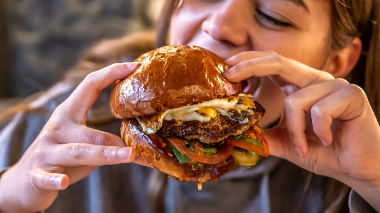 Woman eating a large burger with lots of toppings