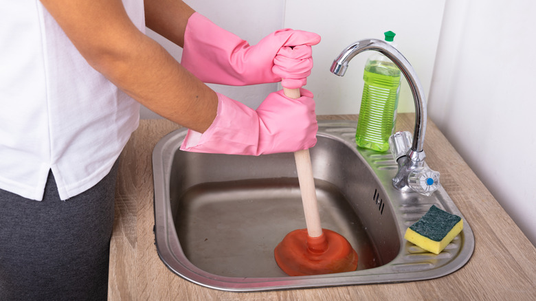 Woman putting plunger in sink
