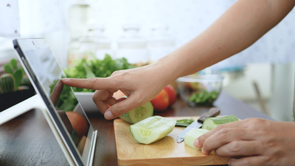 Hand pointing to tablet while cooking