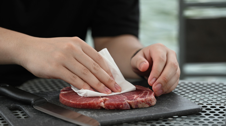 Patting steak dry on cutting board