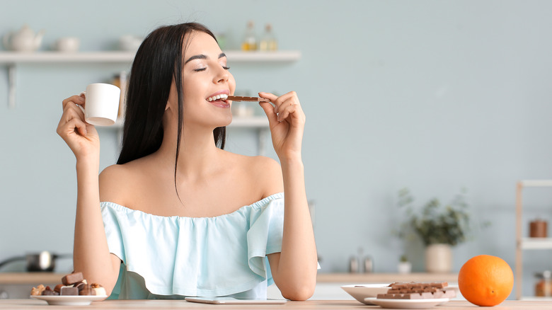 Young woman happily eating chocolate