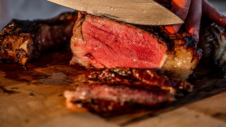 knife slicing rare steak