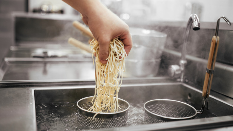 Hands preparing to boil ramen noodles