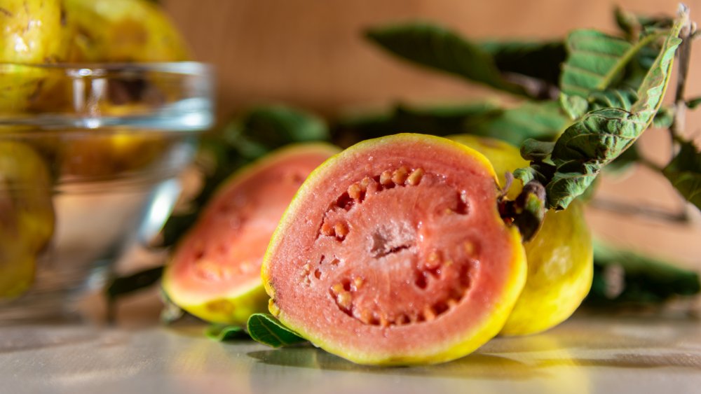 Halved guava fruit pink flesh and a yellow-green skin.