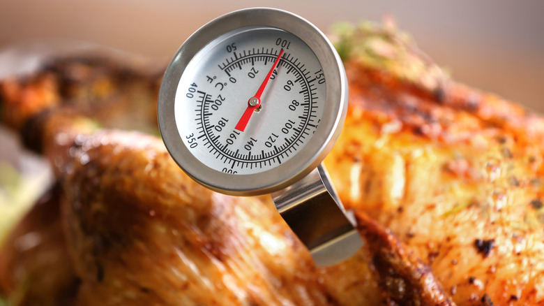 Piece of cooked poultry with a meat thermometer stuck in it. 