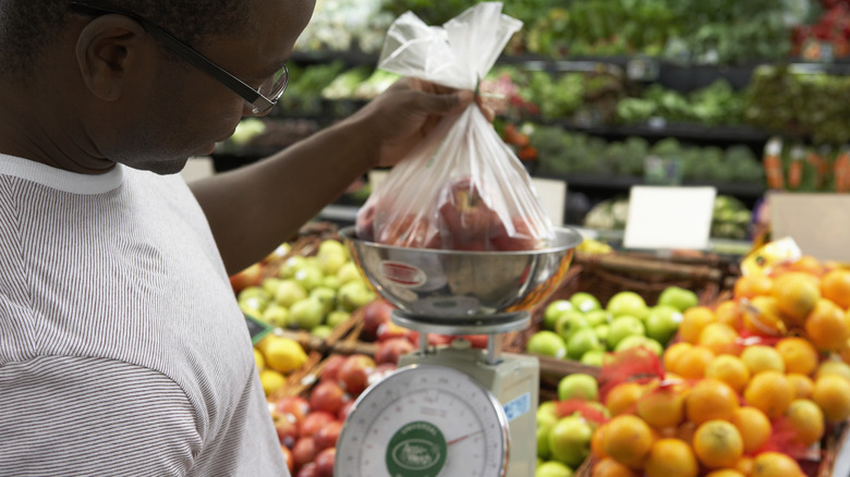 Man weighing a bunch of apples on produce scale