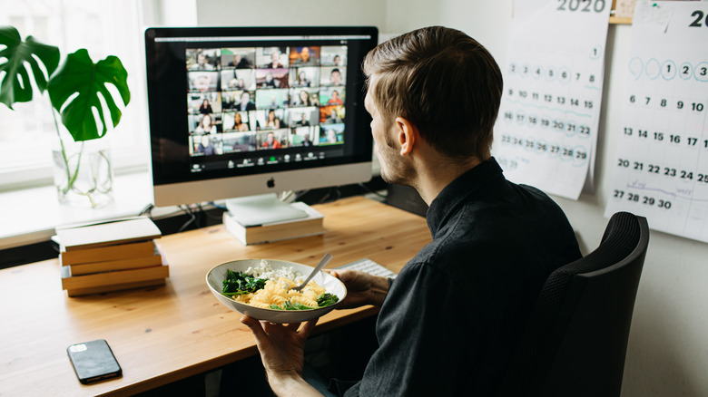 man having lunch in front of computer