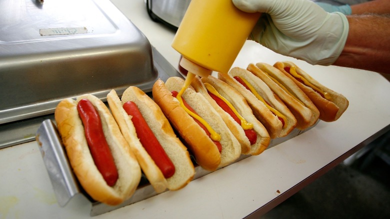 hot dogs getting topped with mustard