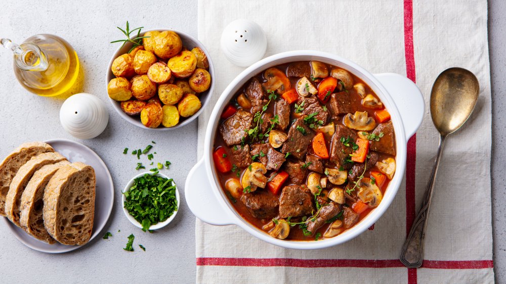 pot of beef stew with bread and potatoes