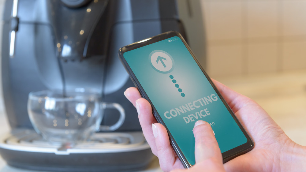 Person using smart phone to program coffee maker