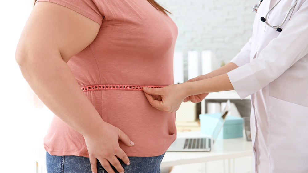 Overweight woman having waist measured