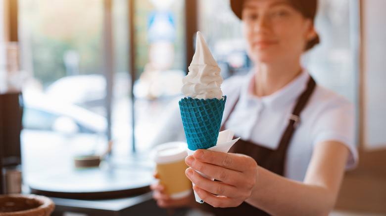Woman holding ice cream cone and coffee