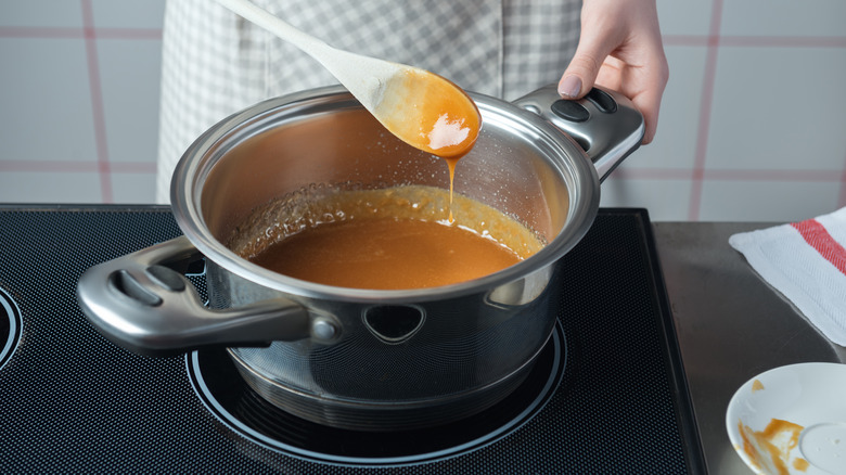 Person stirring caramel sauce on stovetop